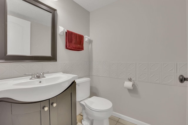 bathroom with toilet, a textured ceiling, wainscoting, tile patterned flooring, and vanity