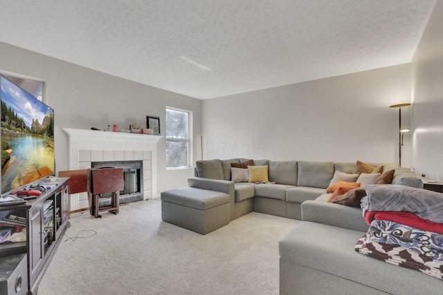 living room featuring a tiled fireplace, carpet flooring, and a textured ceiling