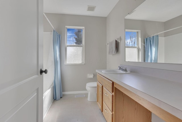 bathroom with tile patterned floors, plenty of natural light, toilet, and vanity