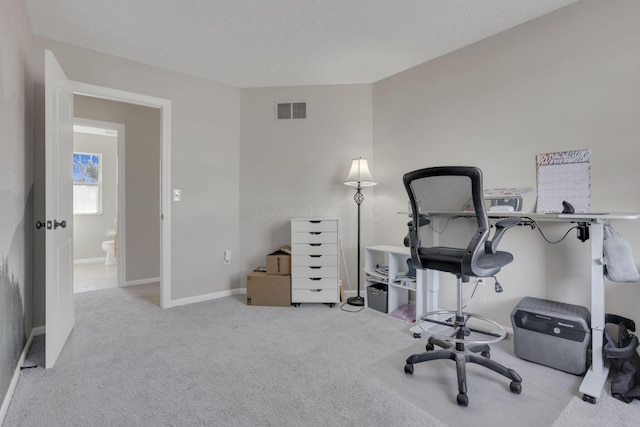 office space featuring a textured ceiling, carpet, visible vents, and baseboards