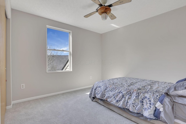 bedroom with carpet flooring, a textured ceiling, a ceiling fan, and baseboards