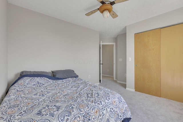 bedroom featuring carpet, baseboards, ceiling fan, a closet, and a textured ceiling