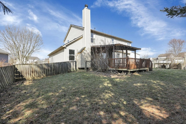 rear view of property with a wooden deck, a yard, a chimney, and fence