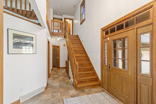 entryway with visible vents, a towering ceiling, stairs, and stone finish floor