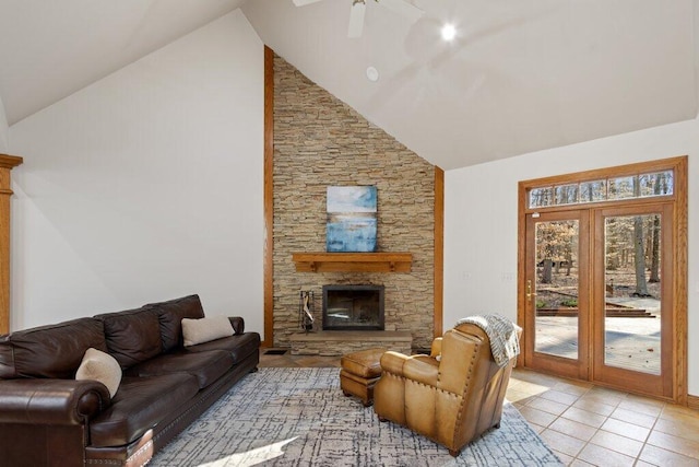 living area with light tile patterned floors, high vaulted ceiling, a stone fireplace, and ceiling fan