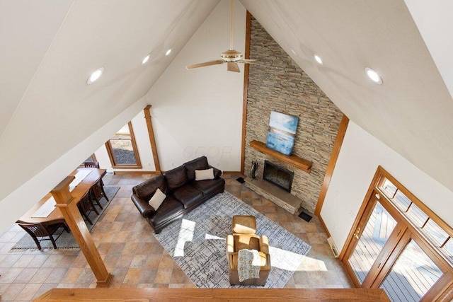 living area with a wealth of natural light, a fireplace, high vaulted ceiling, and baseboards