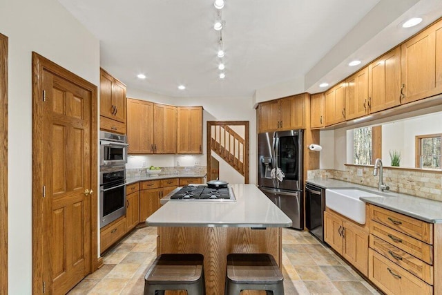 kitchen featuring a kitchen island, light countertops, appliances with stainless steel finishes, a kitchen breakfast bar, and a sink