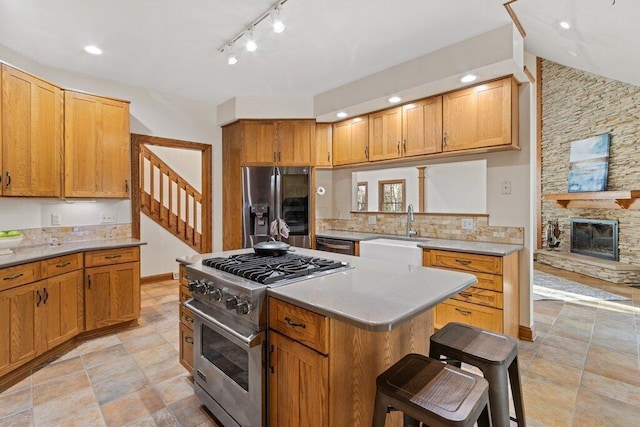 kitchen with a breakfast bar area, a kitchen island, a sink, stainless steel appliances, and light countertops