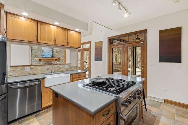 kitchen featuring a sink, decorative backsplash, french doors, appliances with stainless steel finishes, and a center island