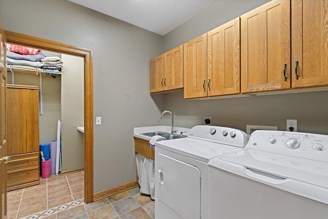 laundry area featuring baseboards, washer and dryer, cabinet space, a textured ceiling, and a sink