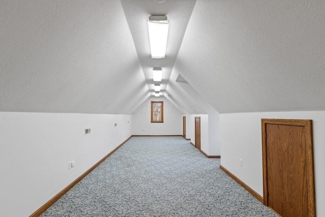 bonus room featuring light carpet, a textured ceiling, baseboards, and lofted ceiling