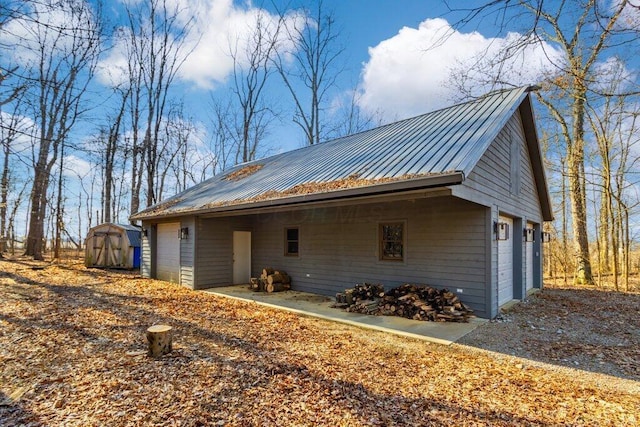 view of front of home with a storage shed, a garage, an outdoor structure, and metal roof