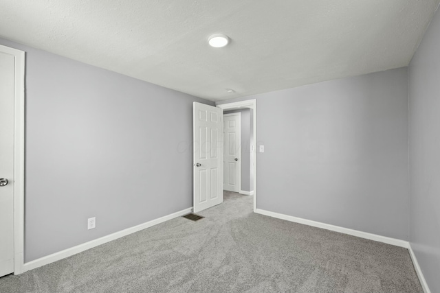 carpeted spare room with visible vents, baseboards, and a textured ceiling