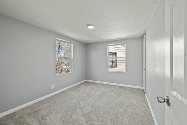 carpeted spare room with baseboards, a wealth of natural light, and a textured ceiling