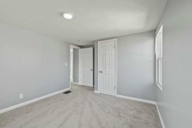 unfurnished bedroom with a closet, visible vents, baseboards, and carpet floors