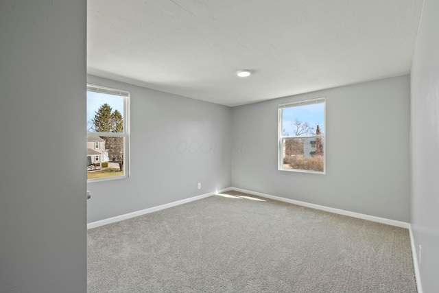 spare room featuring carpet flooring, a healthy amount of sunlight, and baseboards