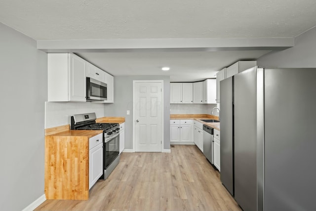 kitchen featuring a sink, stainless steel appliances, light wood-type flooring, and white cabinetry