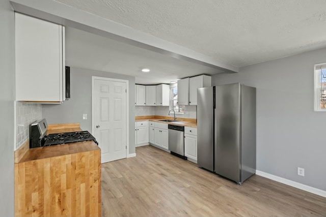 kitchen featuring appliances with stainless steel finishes, wood counters, light wood-style floors, and a sink