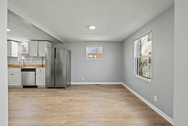 kitchen featuring white cabinets, light wood-style flooring, baseboards, and stainless steel appliances