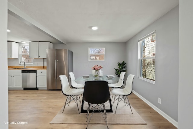 dining area with a wealth of natural light, baseboards, and light wood-style floors