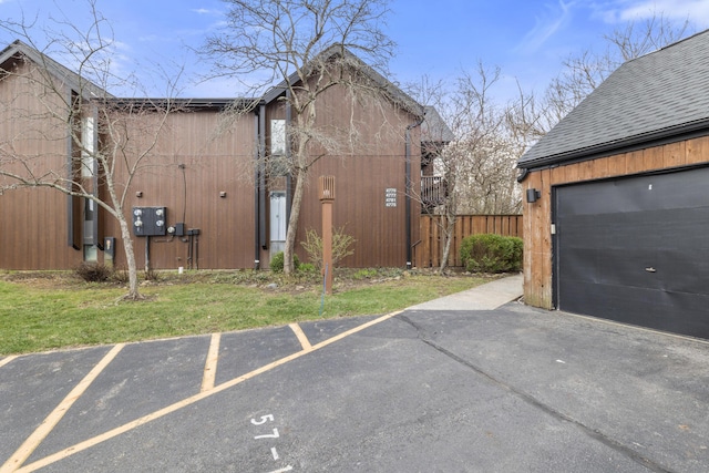 exterior space with roof with shingles, a garage, and fence