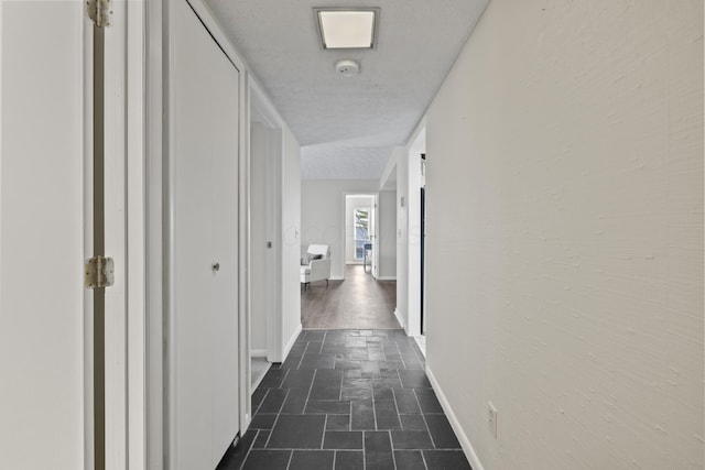 corridor featuring baseboards and stone finish flooring
