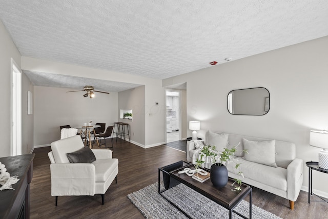 living room featuring a ceiling fan, a textured ceiling, baseboards, and wood finished floors