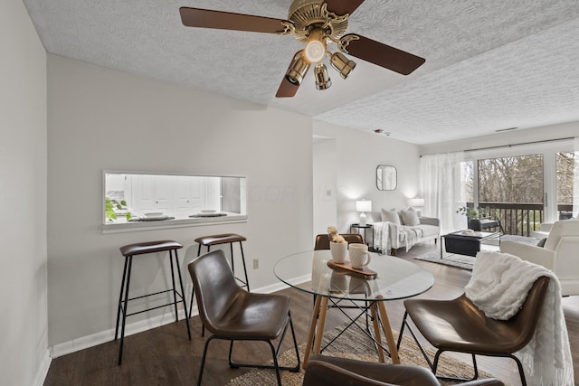 living room with a ceiling fan, a textured ceiling, baseboards, and wood finished floors