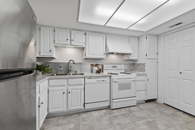kitchen with custom range hood, a sink, white cabinetry, and white appliances