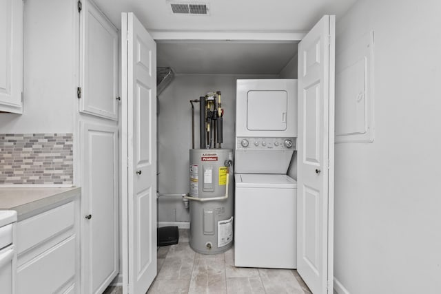 clothes washing area featuring stacked washer and dryer, electric water heater, laundry area, and visible vents