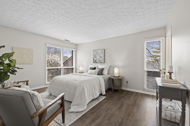 bedroom with dark wood-style floors, multiple windows, and baseboards