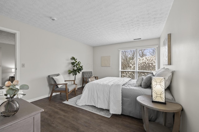 bedroom featuring visible vents, a textured ceiling, baseboards, and dark wood finished floors