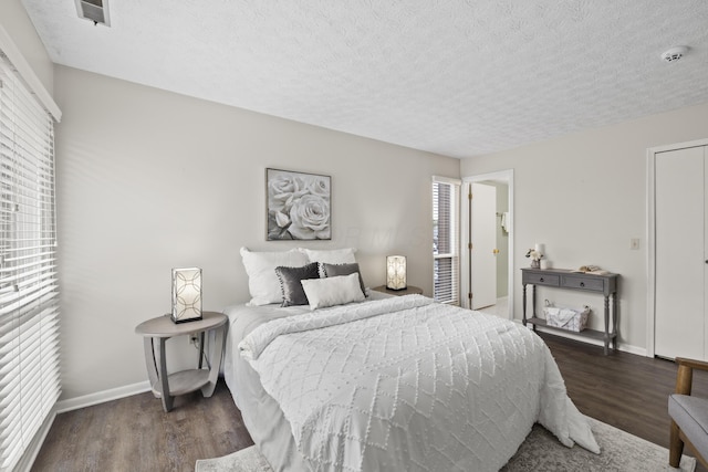 bedroom with baseboards, a textured ceiling, and wood finished floors