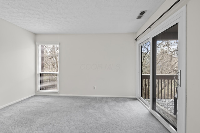 unfurnished room with baseboards, carpet flooring, a textured ceiling, and visible vents