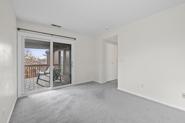 carpeted spare room featuring baseboards and visible vents