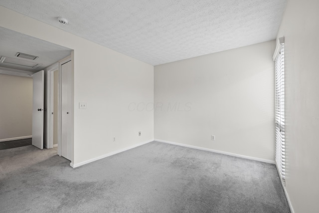 empty room with baseboards, a textured ceiling, and carpet