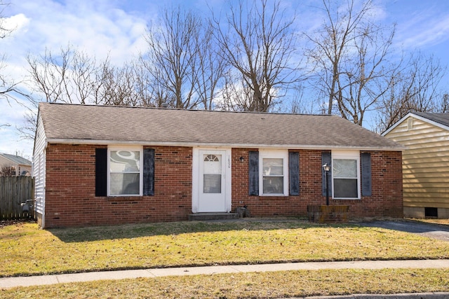 view of front of house with brick siding, a front lawn, and roof with shingles