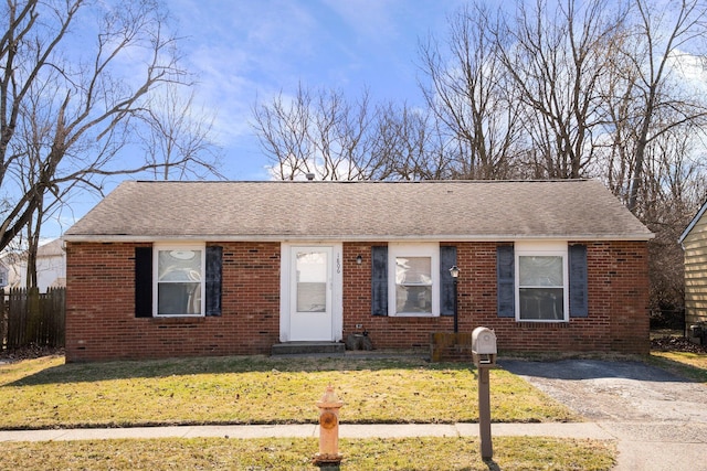 view of front of home with brick siding, a front lawn, and a shingled roof