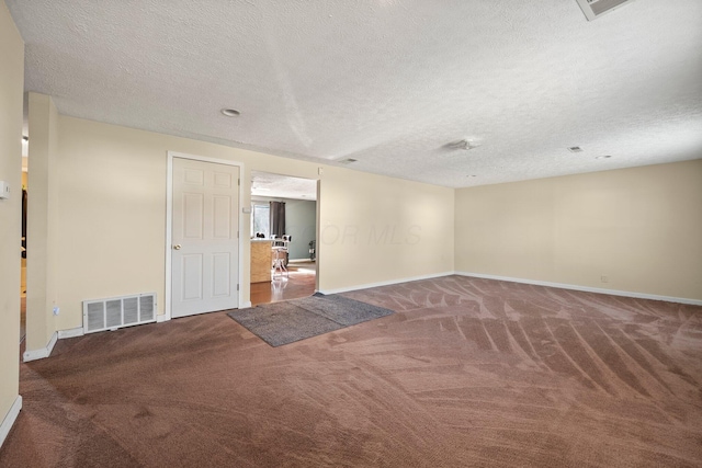 carpeted empty room featuring baseboards, visible vents, and a textured ceiling