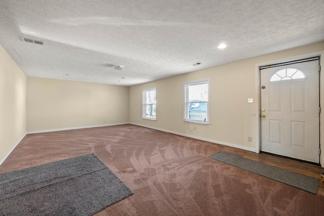 entrance foyer with visible vents, a textured ceiling, baseboards, and carpet