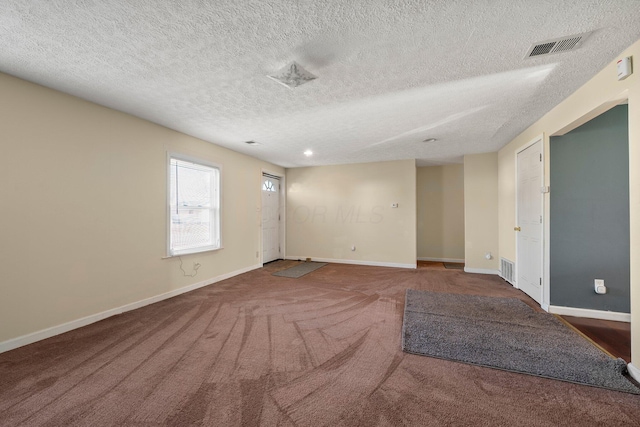 carpeted empty room featuring visible vents, baseboards, and a textured ceiling