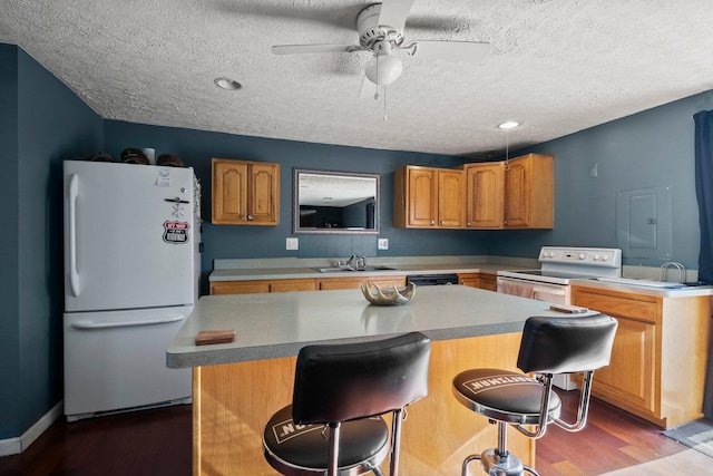 kitchen with a kitchen island, dark wood-type flooring, a breakfast bar, white appliances, and a ceiling fan