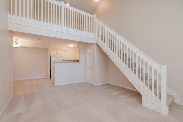 interior space featuring a towering ceiling, baseboards, and carpet floors