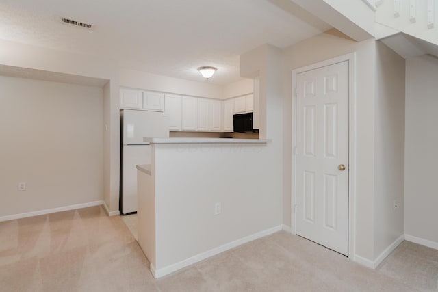 kitchen with white cabinetry, light colored carpet, visible vents, and freestanding refrigerator