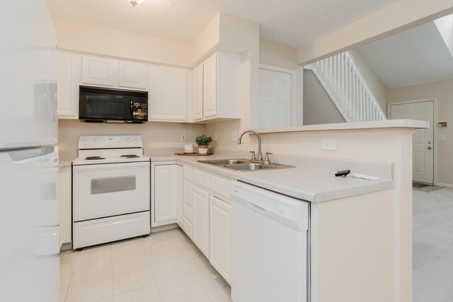 kitchen featuring white appliances, white cabinetry, a peninsula, and a sink