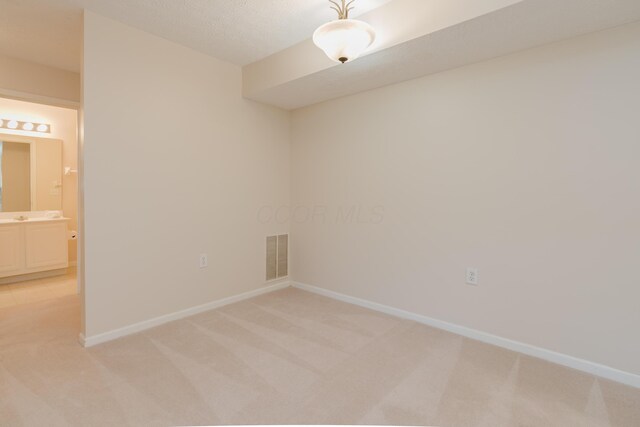 empty room with visible vents, light colored carpet, and baseboards