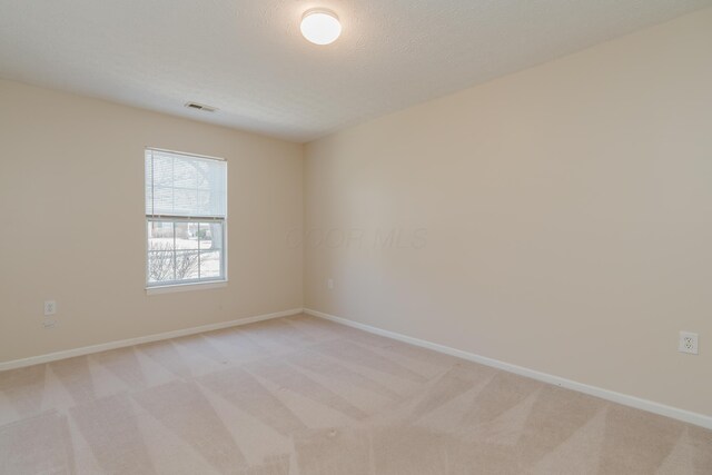 unfurnished room with visible vents, baseboards, and light colored carpet