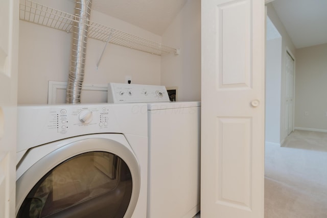 clothes washing area featuring washer and clothes dryer, laundry area, light carpet, and baseboards