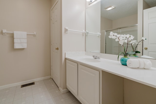 full bath featuring visible vents, a textured ceiling, a shower stall, baseboards, and vanity