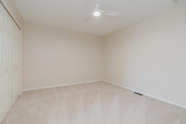 unfurnished bedroom featuring baseboards, visible vents, light carpet, and a closet